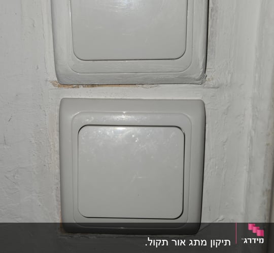 שני מתגי חשמל לבנים על קיר לבן
